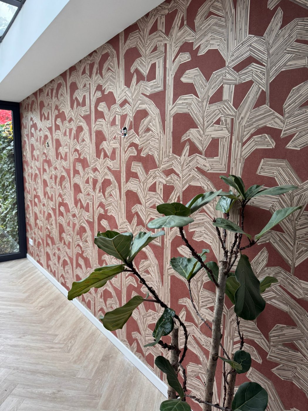 Terracotta wand met wit bladmotief onder een schuine kap, Woonkamer